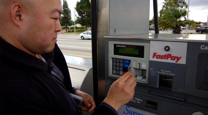 spending-on-gas Man inserting card to buy cheap gas at a GasBuddy recommended location.
