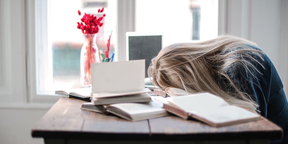 Woman with face on table suffering burnout in front of computer.