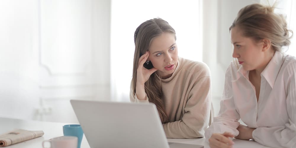Women at desk with laptop discussion succession.