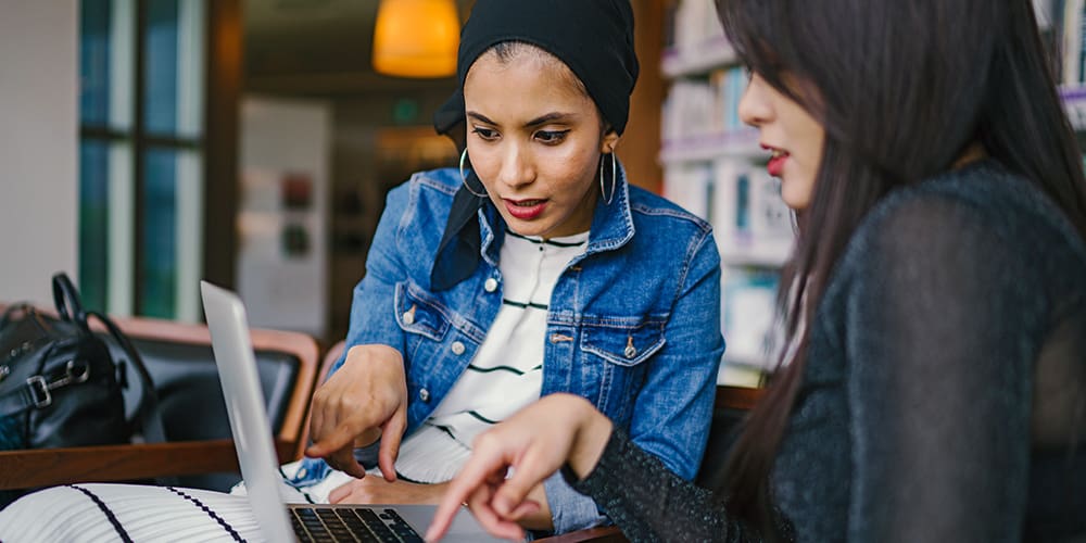Two women working at a laptop, no need to pivot business.