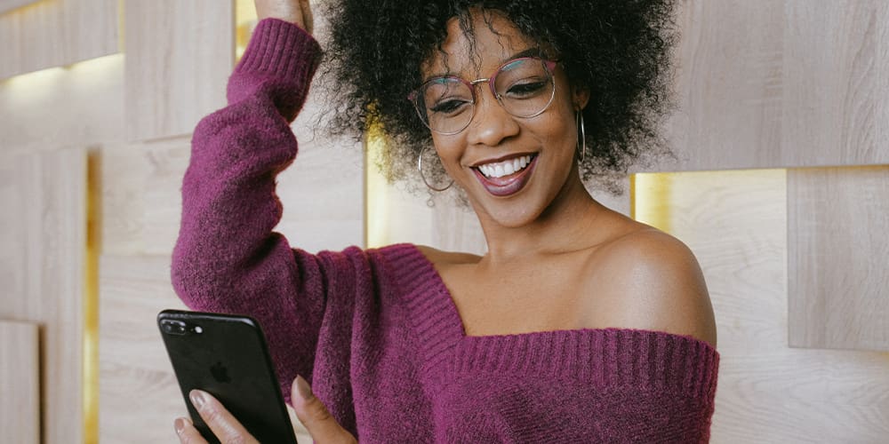 Woman talking on Clubhouse on her iPhone with a big smile.