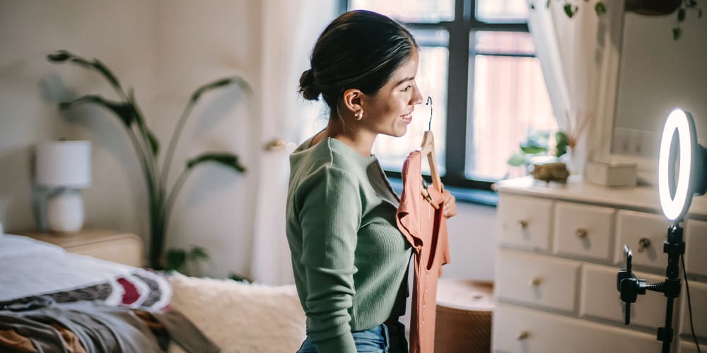 Woman holding peach dress up for a video ad on Pinterest Premiere with a Ring light for better lighting.