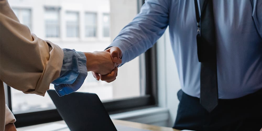 Handshake Two business partners shaking hands as part of a Tiger Global acquisition deal.