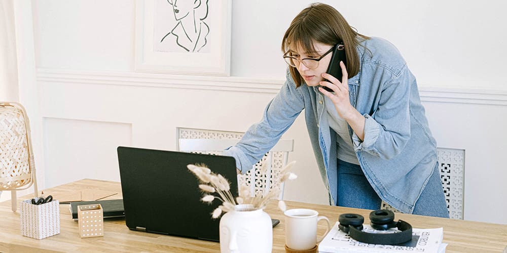 Amazon sellers leaned over a laptop while on the phone, checking data mid-conversation.