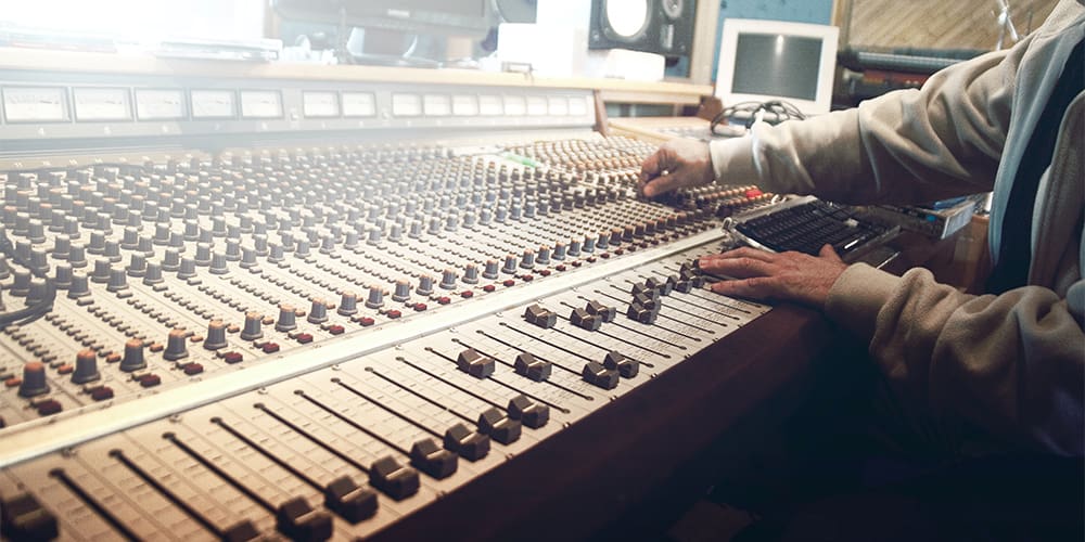 Person at audio mixing table, preparing audio branding