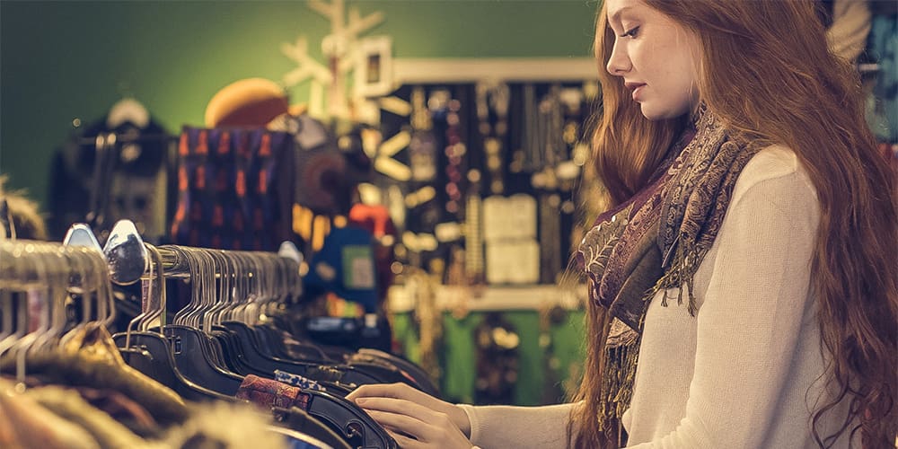 Woman looking at a rack of clothes in a second hand thrift store