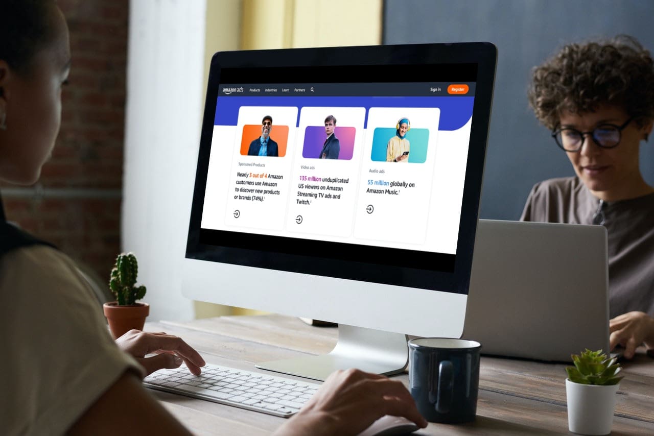 Amazon Advertising Two African American women work at their desks, one viewing Amazon's advertising landing page.