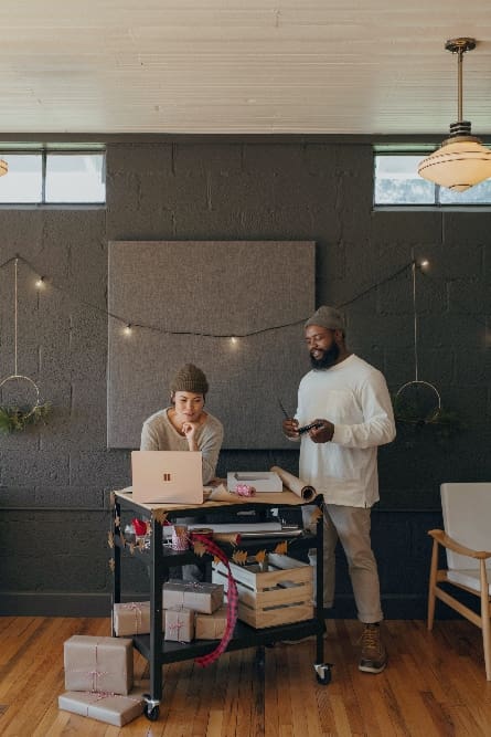 Two people looking at laptop in office for wrapping gifts. 