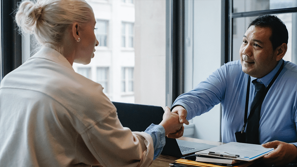 A man and woman shaking hands over a business table, agreeing on a gig workers contract