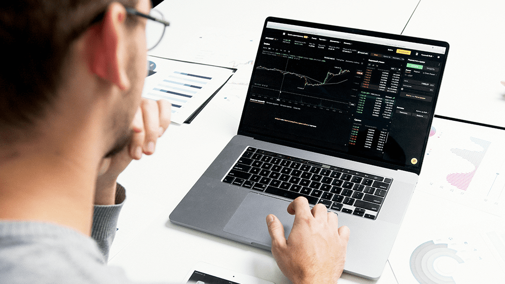 Person looking a computer with stock market open to a Reddit page as they go public.