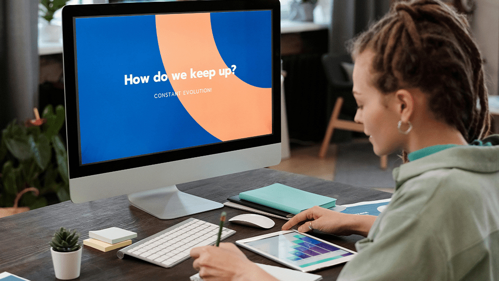A woman sitting in front of a computer with the screen highlighted on a presentation saying