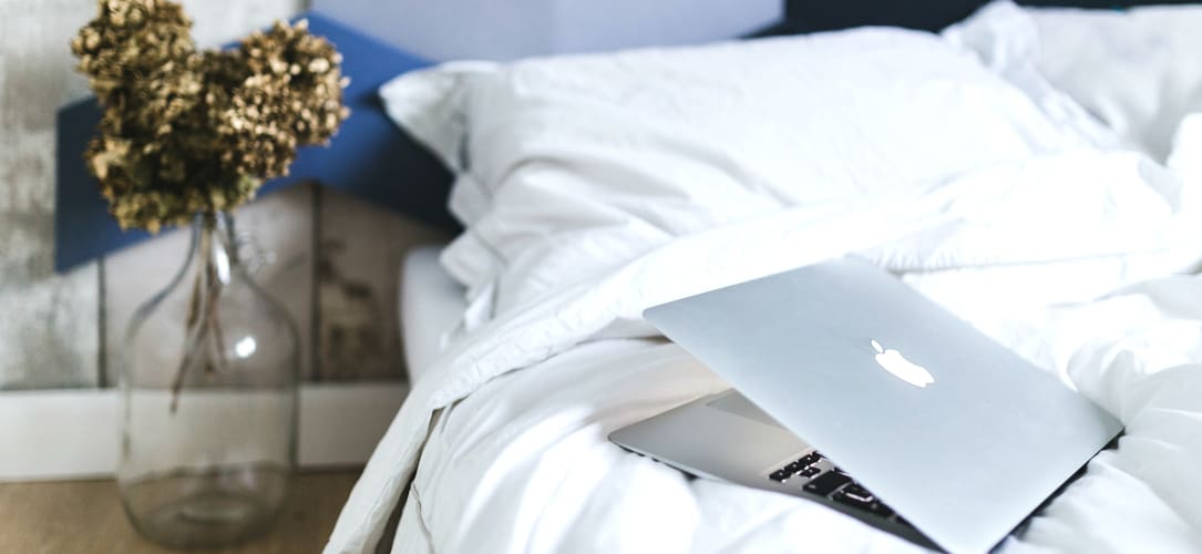 Laptop on bed representing morning routine.