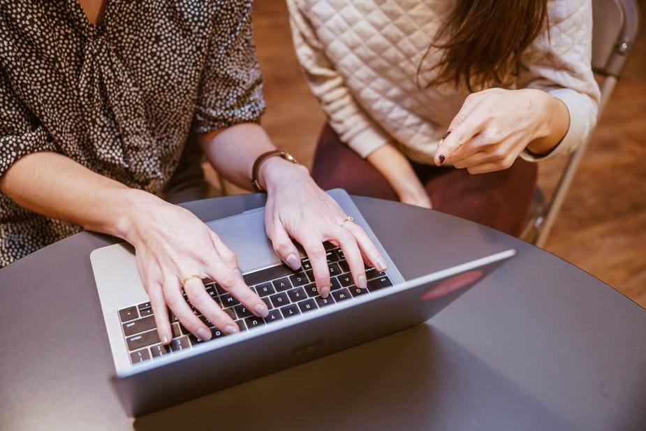 Two women looking at a laptop representing leaders talking about work-life balance.