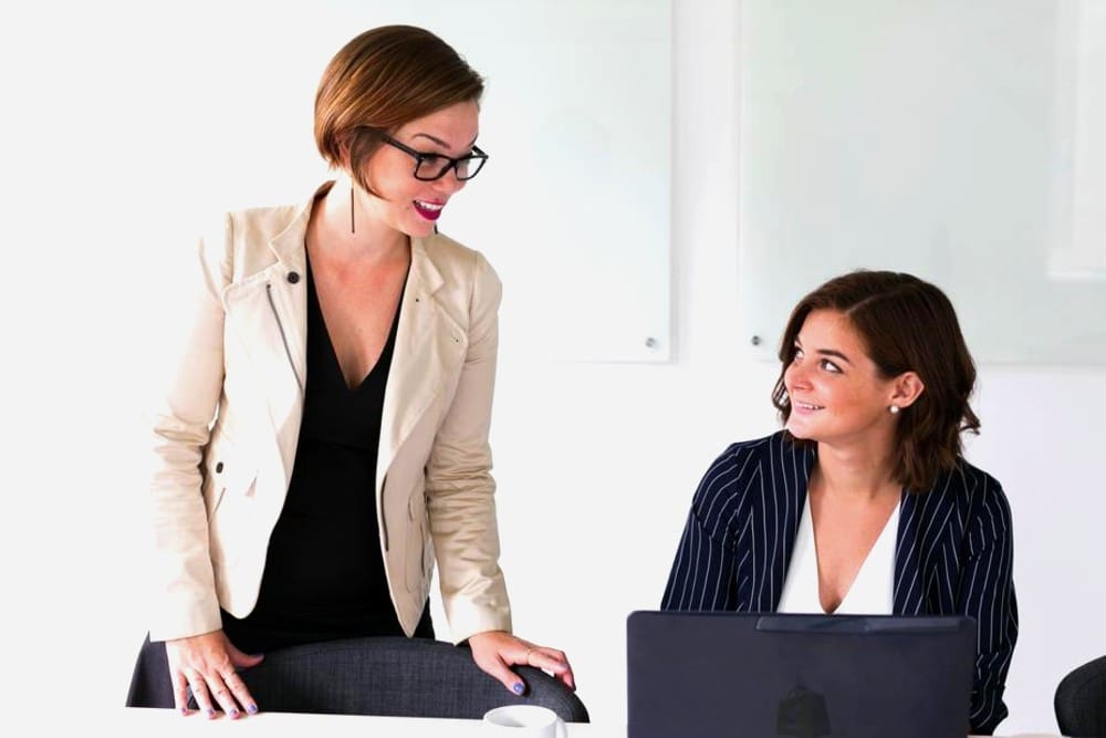 Two friends in the office smiling and talking.