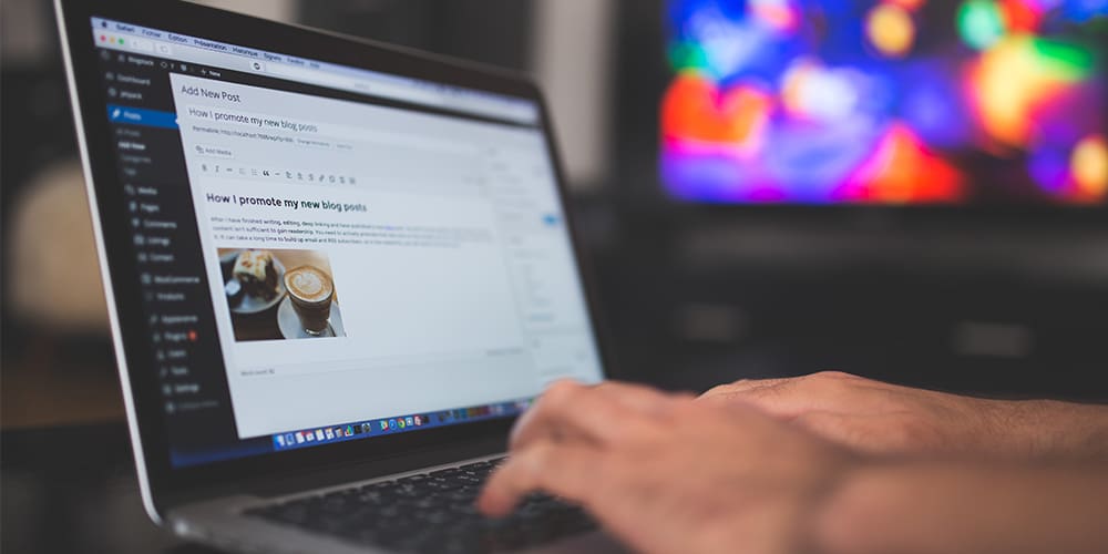 Blog post being written on laptop in front of colorful TV