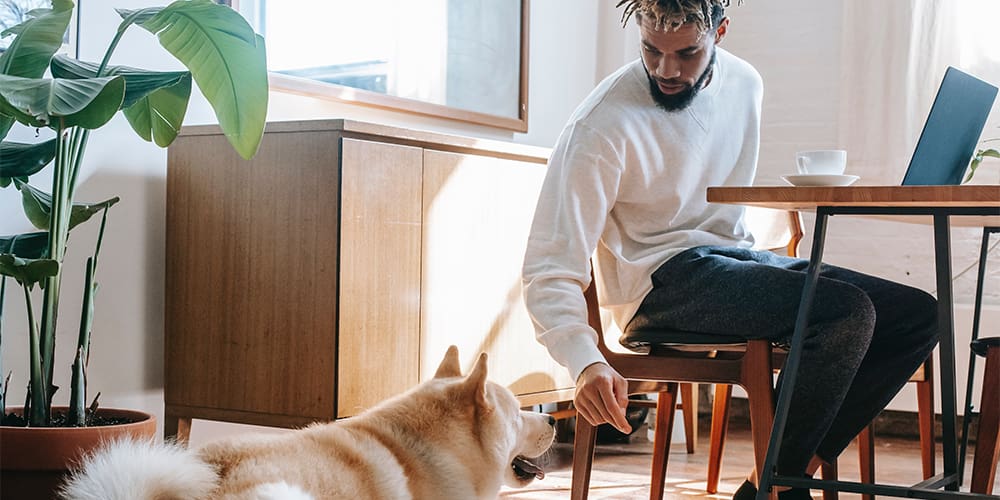 Man sitting in a home with dog at his feet, subject to housing discrimination.