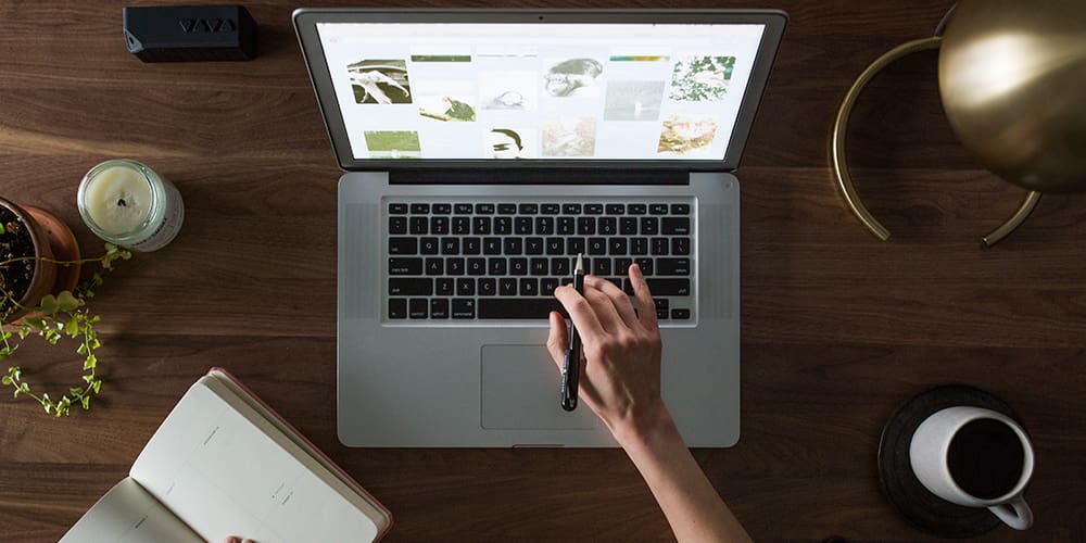 An overhead look at a person working on a no-code design website on a laptop on a desk.