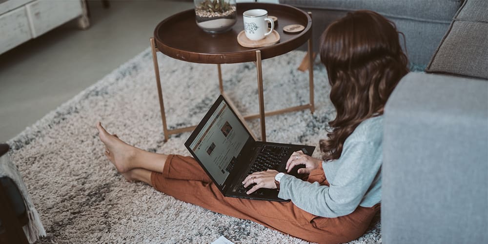 reviews Woman seated on ground writing cold email to clients.
