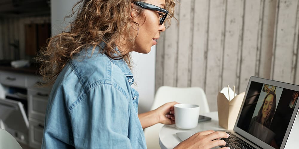 Video call and use of social media as two small business women chat over coffee.