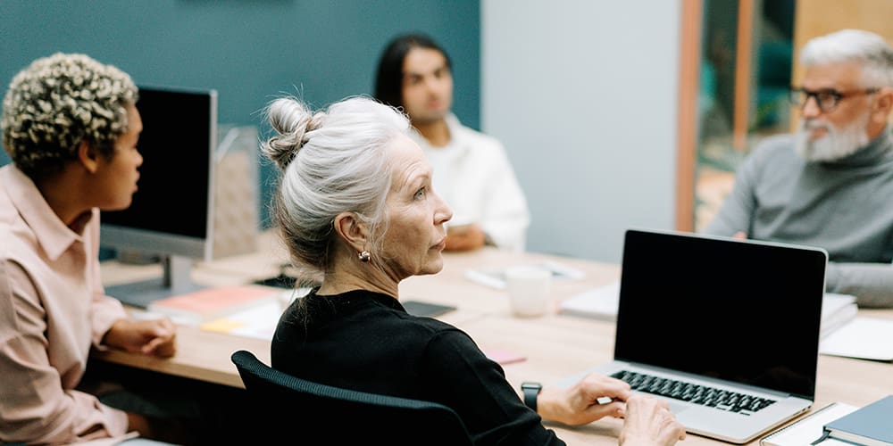 A diverse range of employees sit at a table, with learning about how to avoid age discrimination.