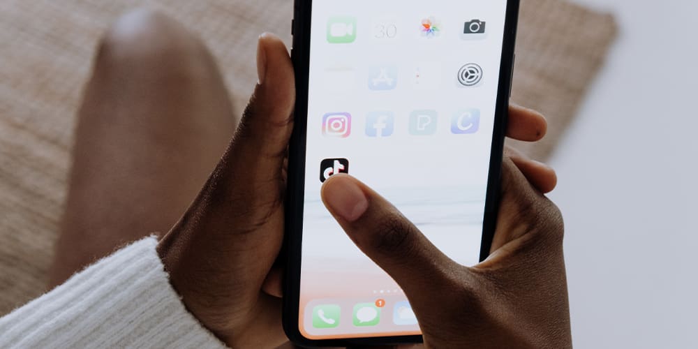 Hands holding a phone about to open the TikTok app
