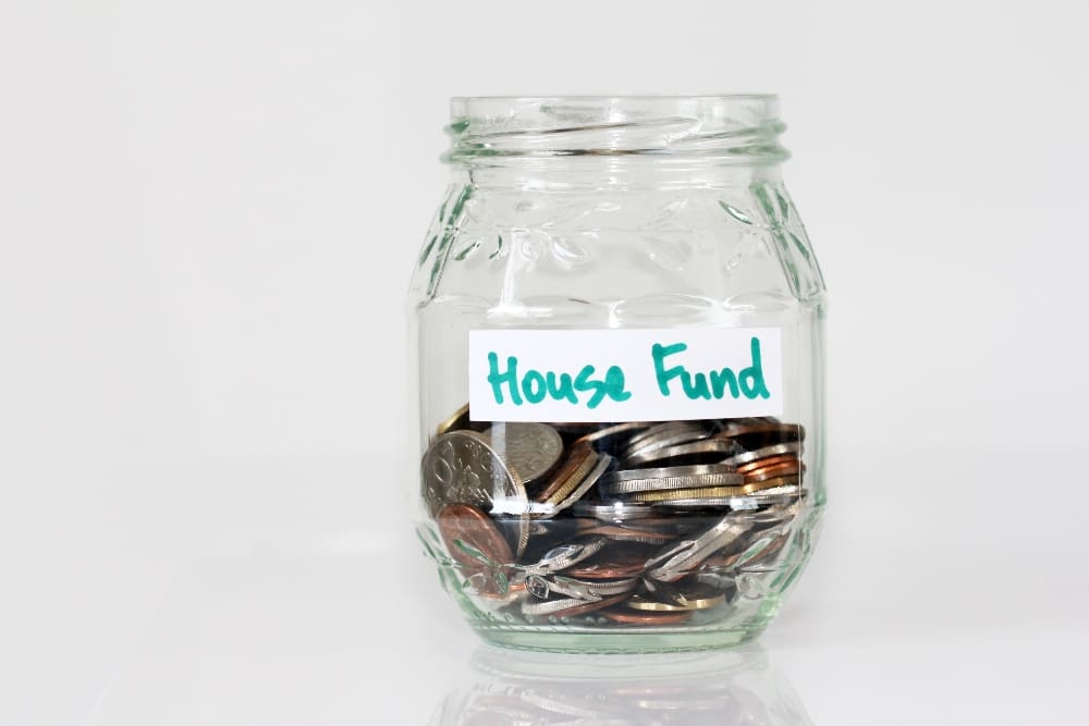 Glass jar of coins labeled House Fund.