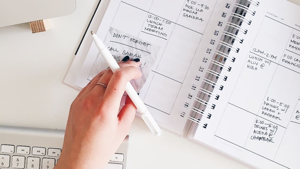 Person writing in calendar representing goals and habits