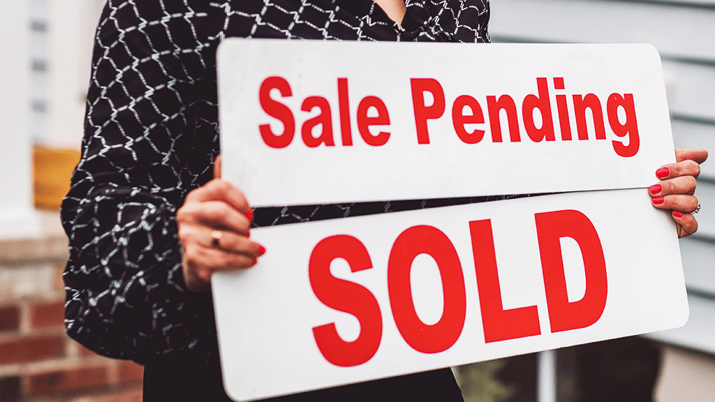 A person with painted red nails holding a 'sale pending' and a 'sold' sign in a home selling marketplace.