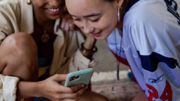 Two women looking at TikTok on the phone representing social media addiction