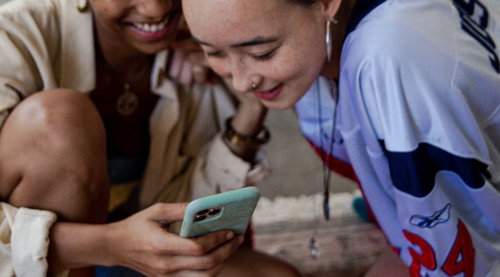 Two women looking at TikTok on the phone representing social media addiction