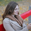 A woman sitting on a red park bench in the fall using her smartphone setting up moving.