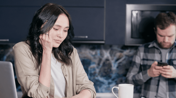 A woman sits next to her computer with an anxious expression, worried about layoffs.