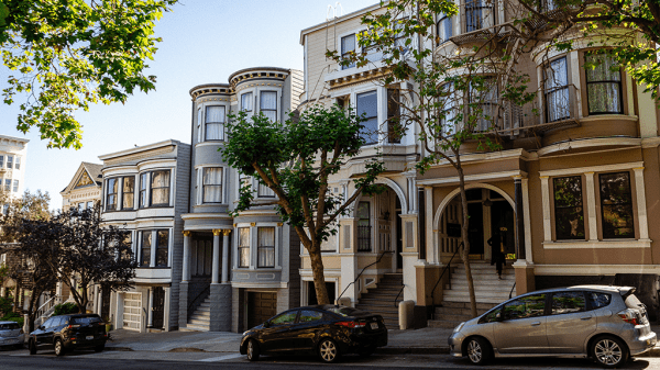 A city street showing close together housing with different home prices