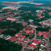 An aerial view of a suburban neighborhood with many occupied and vacant homes with red rooves surrounded by green trees.