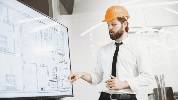 A man in an orange hard hat reviews eminent domain while showing off a schematic for a new building.
