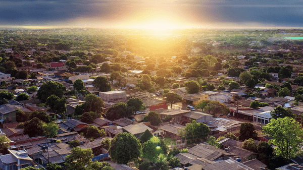 An aerial view of a neighborhood with the sun rising just beyond the swath of houses with lower interest rates.