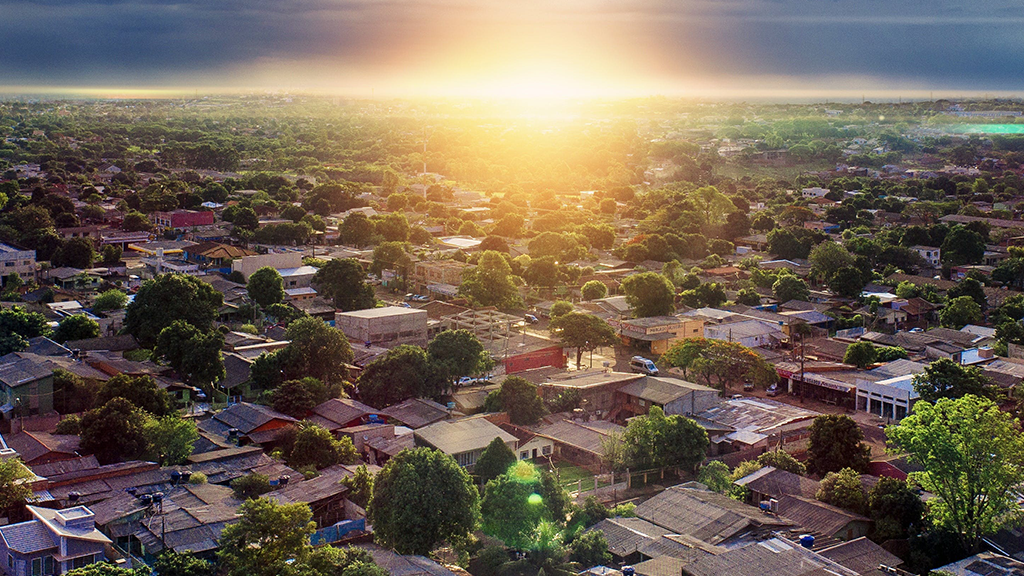 An aerial view of a neighborhood with the sun rising just beyond the swath of houses with lower interest rates.