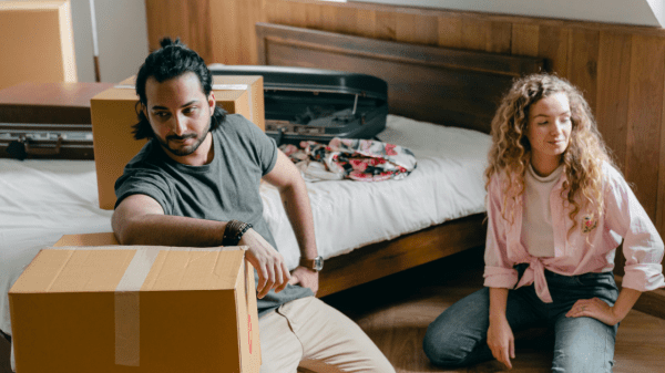 A man and a woman unpacking boxes inside of a house after dealing with landlords sexually harassing them.